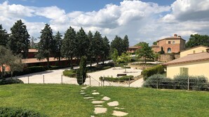 Un jardín ajardinado con un sendero de grava, rodeado de árboles y edificios.