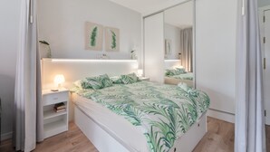 Un dormitorio con cama, mesitas de noche, un espejo y decoración en la pared.