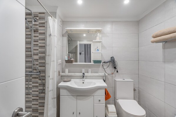 Un baño moderno con ducha, lavamanos, inodoro y toallero.