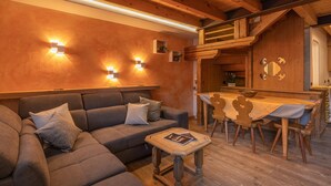 Un salon chaleureux avec un canapé, une petite table et un coin repas en bois avec des chaises.