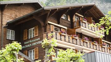 A wooden hotel building with balconies and a sign that reads "Hotel Restaurant Waldhaus Grichting."