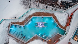 A swimming pool surrounded by snow, with steps leading into the pool and a few people around it. - Hotel Waldhaus (Leukerbad)