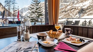 A breakfast table with croissants, bread, a bowl of soup, a plate of ham and cheese, and a cup of coffee. - Hotel Waldhaus (Leukerbad)