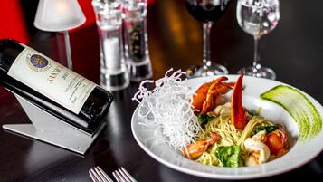 A dining table with a plate of food, a bottle of wine, and salt and pepper shakers.