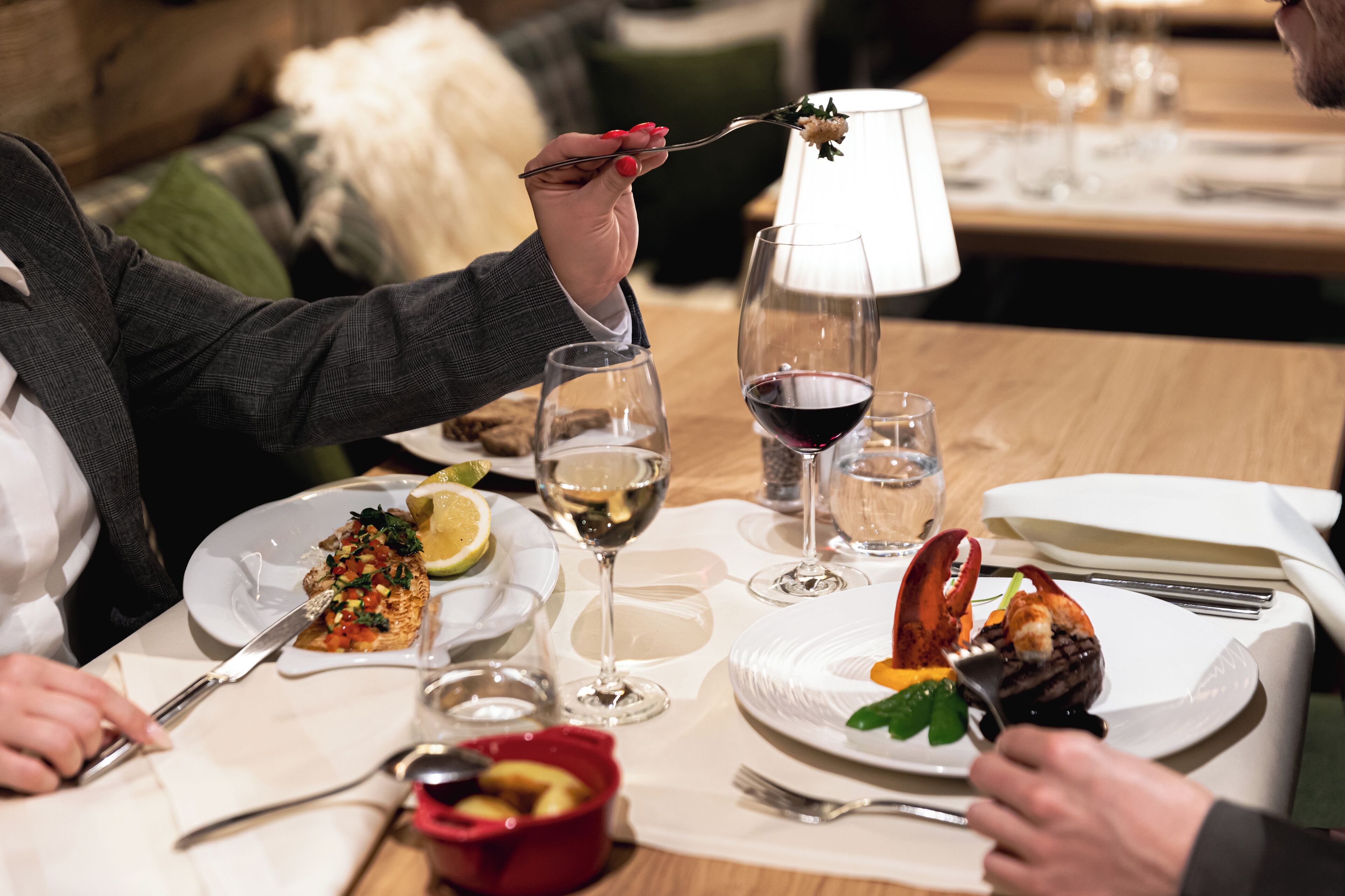 A dining table set with plates of food, wine glasses, and cutlery.