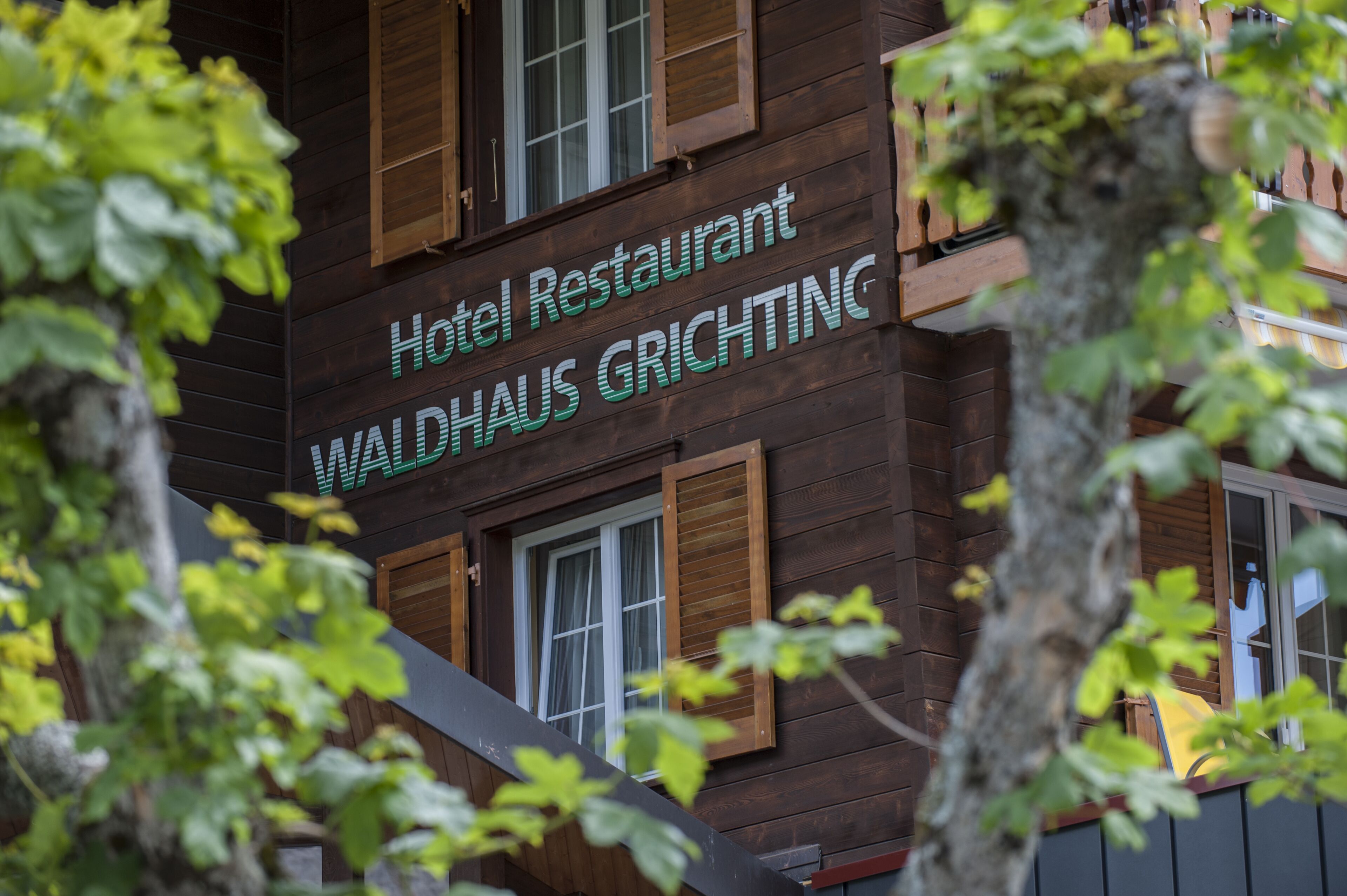 A hotel restaurant sign with the name "WALDHAUS GRICHTING" on a wooden building facade.