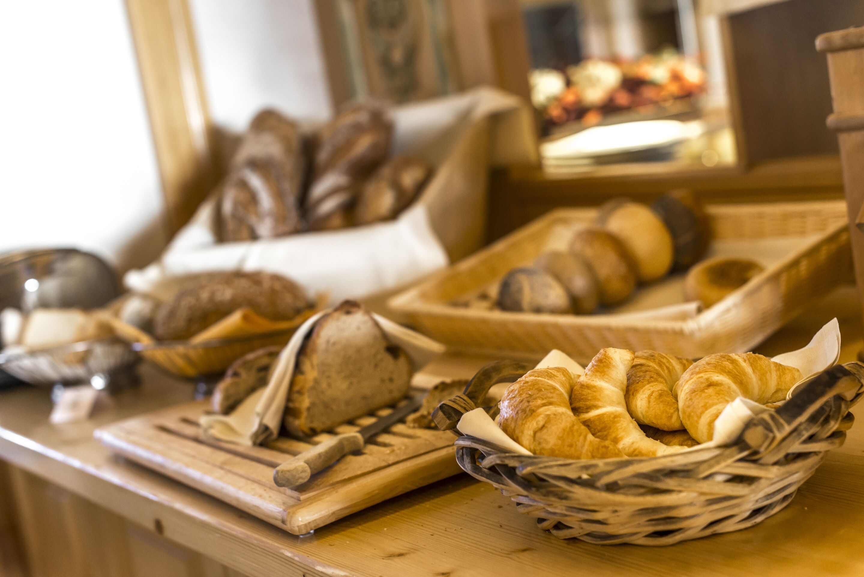 A variety of breads and pastries on a wooden counter.