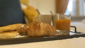 Ein Tablett mit Croissants und einem Glas Orangensaft auf einem Tisch.