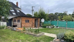 Eine Holzhütte mit Satellitenschüssel, umgeben von einem gepflegten Garten und einem grünen Zaun.