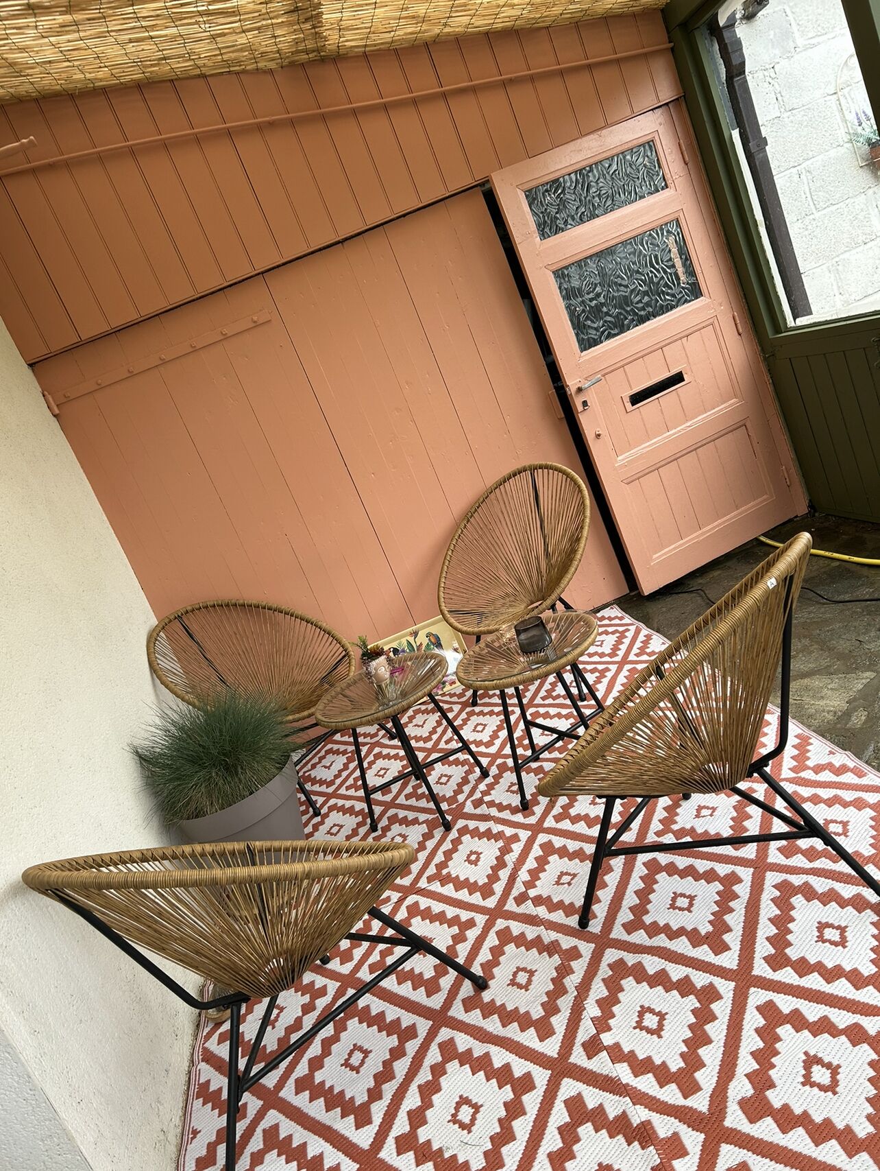 A cozy outdoor seating area with wicker chairs and a patterned rug.