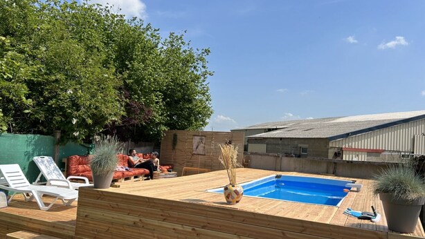 Eine Holzterrasse mit Pool, Liegestühlen und Kübelpflanzen.