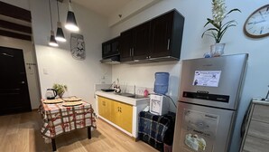 Una cucina compatta con frigorifero, microonde e un piccolo tavolo con tovaglia.