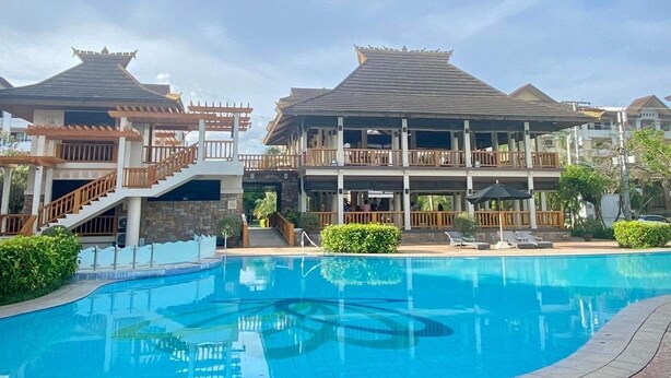 Un hotel con piscina, diversi balconi e uno stile architettonico tradizionale.