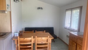 Et træspisebord med fire stole, en mørkeblå bænk og et træskab med et vindue over.