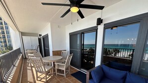 A balcony with a table and chairs, a blue sofa, and a view of the beach. - "Newly remodeled Breakers East 303" Gulf front 3BR/ 2BA Beach setup included (Destin)