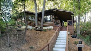 A cabin with a wooden staircase leading to a covered porch.