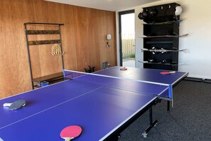 A room with a ping pong table, a coat rack, and a shelf with skis. - Northlake Alpine Retreat (Wanaka)