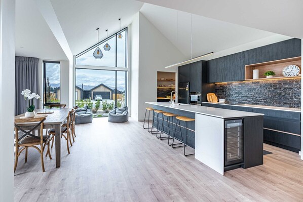 A modern kitchen with a large island, bar stools, and a built-in oven.