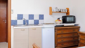 Kompakti keittiö, jossa on pesuallas, mikroaaltouuni, pieni jääkaappi ja puukehikoiset kaapit.