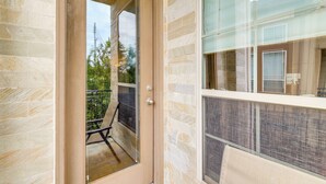 A modern building with a glass door leading to a balcony with a chair. - Dtwn Houston Home Near Stadiums: WFH Friendly! (Houston)