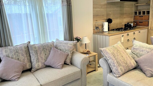Ein Wohnzimmer mit zwei Sofas, einem kleinen Beistelltisch und einer Küchenzeile mit Gasherd und Schränken.