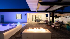 Una terrazza esterna con una focolare, una piscina e una zona relax coperta.