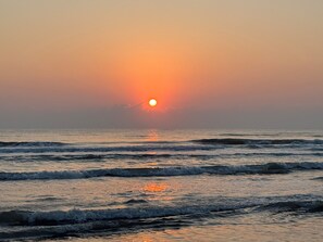 Um pôr do sol sobre o oceano com ondas.