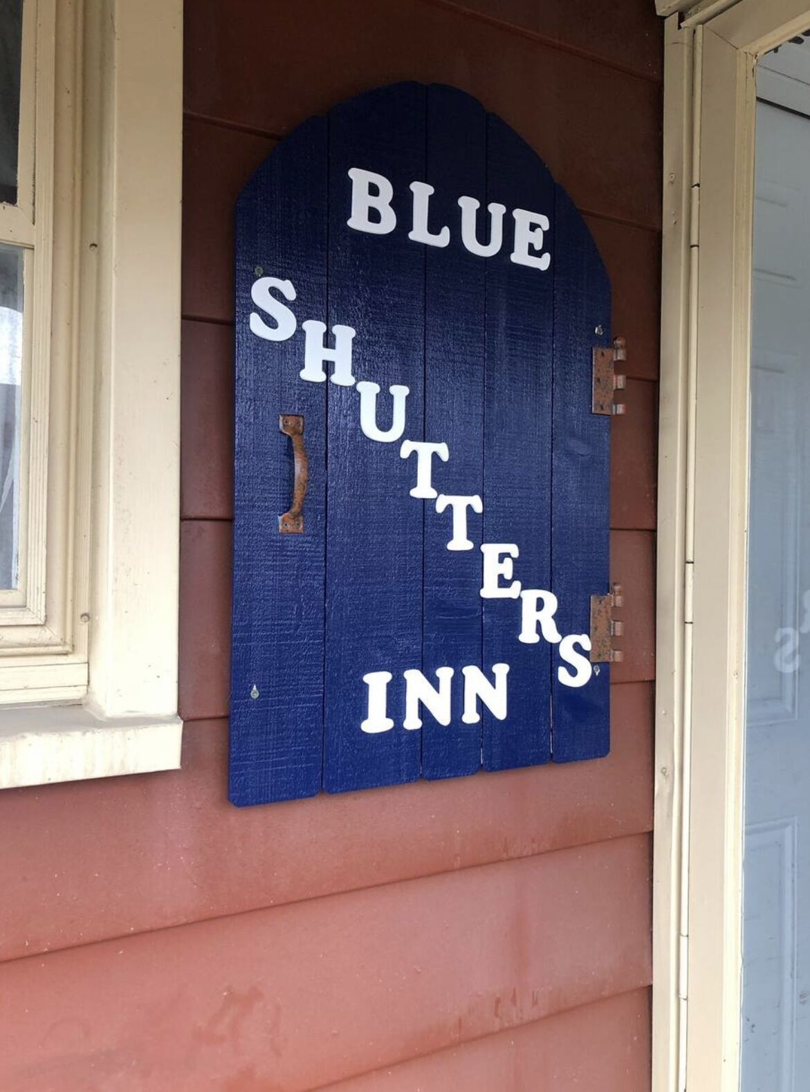 Un letrero azul con la frase 'BLUE SHUTTERS INN' sobre un edificio.
