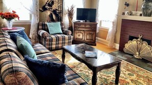 Un salon comprenant un canapé, un fauteuil, une table basse, une cheminée et un téléviseur.