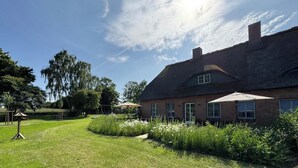 Un'ampia casa in mattoni con tetto di paglia, circondata da un giardino curato e da un'altalena.