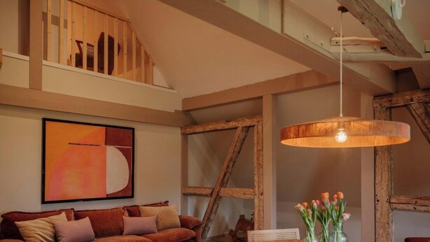 Una stanza con una zona mansardata, un quadro astratto di grandi dimensioni, un soffitto in legno e un lampadario.