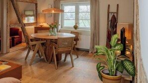 Una stanza accogliente con un tavolo da pranzo in legno, sedie e un'ampia finestra con tende.