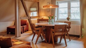 Un'accogliente sala da pranzo con un tavolo rotondo in legno e sedie, un lampadario e vista all'esterno attraverso una finestra.