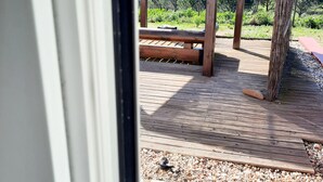 A wooden deck with a stone floor, a wooden pergola, and a view of a vineyard.