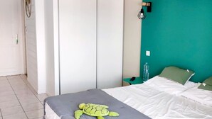 A bedroom with a bed, a teal accent wall, a grey blanket, and a green pillow. - CHAMBER ANTILLAISE (Trois ilets)