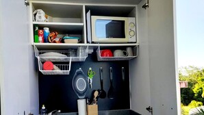 A compact kitchenette with a microwave, sink, and various kitchen utensils. - CHAMBER ANTILLAISE (Trois ilets)