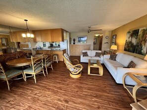 A spacious living area with a dining table, wicker chairs, a sofa, and a coffee table. - Maui Sunset Vacation Rentals B219 (Kihei)