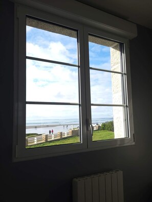 A window with a view of a beach and a stone wall. - Lestrevet beach house (Plomodiern)