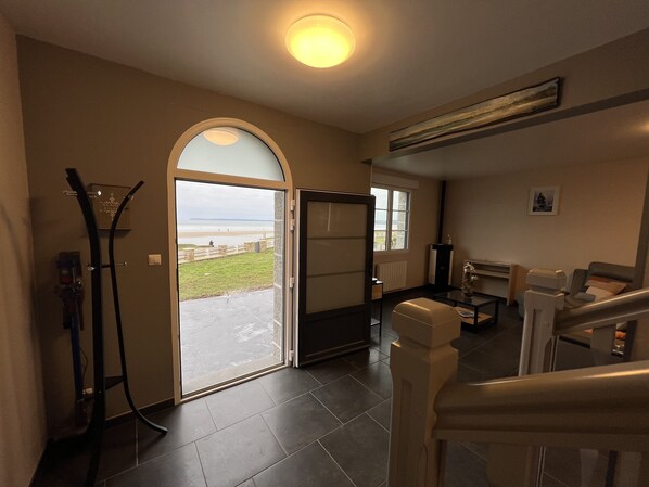 A spacious living area with a large glass door leading to a balcony overlooking a beach.