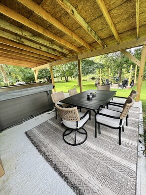 Eine Terrasss mit Holz-Pergola, Grill und Esstisch mit Stühlen.