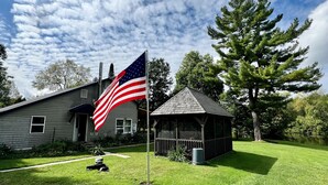 A house with a flagpole, a small gazebo, and a lawn. - 4 season Adventures! Waterfront, *Hot tub*<br>Deer River Paradise! (Brasher falls)