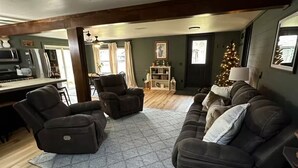A living room with a sectional sofa, two recliners, a coffee table, a fireplace, a kitchen in the background, and a Christmas tree. - 4 season Adventures! Waterfront, *Hot tub*<br>Deer River Paradise! (Brasher falls)