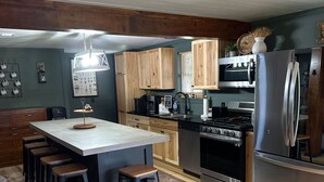 A kitchen with a central island, wooden bar stools, a stainless steel refrigerator, and a stove. - 4 season Adventures! Waterfront, *Hot tub*<br>Deer River Paradise! (Brasher falls)