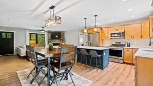A modern kitchen with wooden cabinets, stainless steel appliances, and a central island with bar stools.