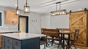 A modern kitchen with a central island, wooden cabinets, and pendant lighting.