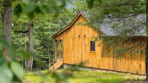 A wooden cabin with a sloped roof, a small window, and a staircase leading to a porch.