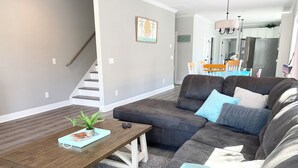 Ein modernes Wohnzimmer mit einem Ecksofa, einem Holztisch und einer Treppe zu einer weiteren Ebene.