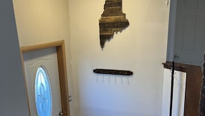 Un escalier avec une rampe en bois, un porte-manteau fixé au mur et un élément décoratif en bois au-dessus de la porte.