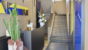 A modern reception area with a reception desk, a staircase, and a cactus plant. - Hotel Gabbani  (Bibbona)