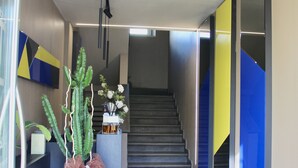 A modern interior with a staircase, a large potted plant, and a minimalist design. - Hotel Gabbani  (Bibbona)